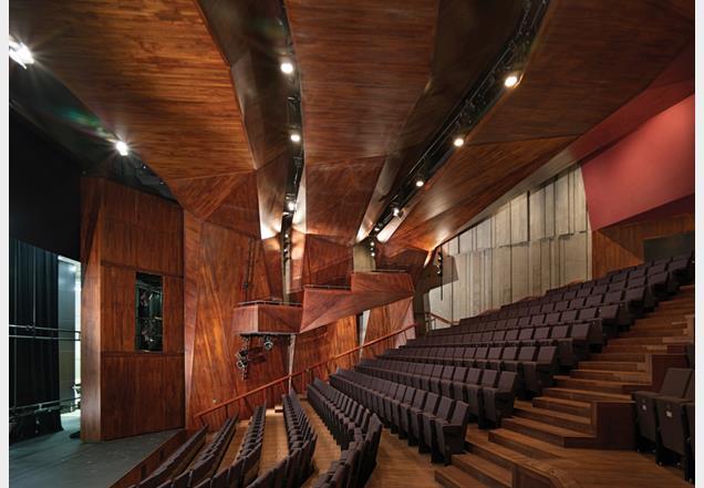 The main auditorium is conceived as a faceted timber grotto, spanned by three lighting arches.